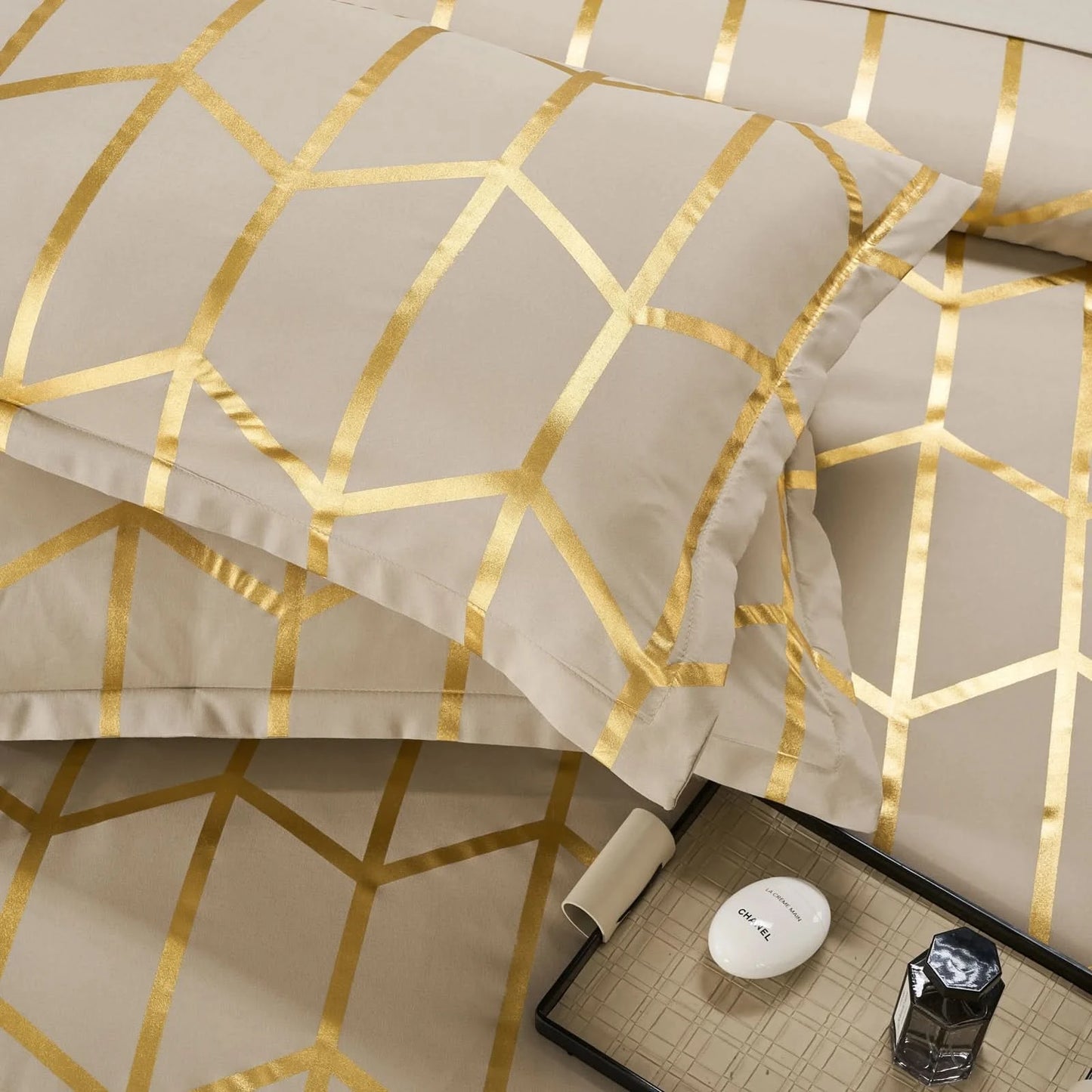 Beige bedding set with gold geometric patterns on a bed.