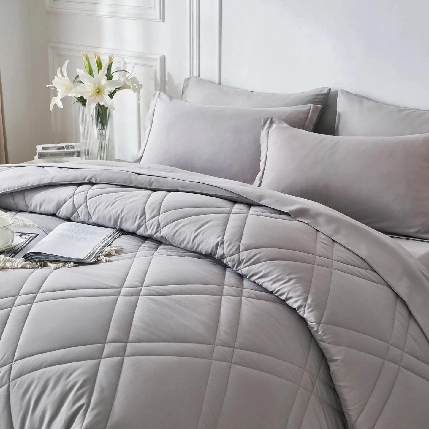Gray quilted comforter set on a bed with pillows and a vase of flowers in the background.
Microfiber bedding set
Queen and King bedding
Soft comforter set
Modern bedroom decor
Machine washable bedding
Polyester comforter
Cozy all-season bedding
Brushed microfiber
Lightweight and warm comforter
Bedding set with pillowcases
