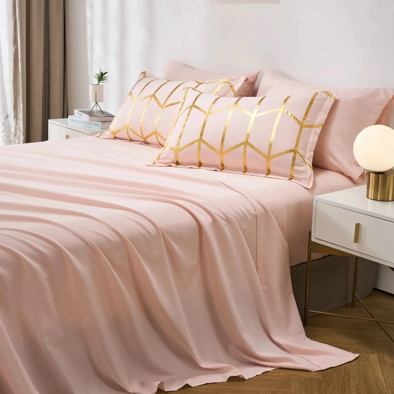 Pink bedding set with gold geometric patterns on a bed in a bedroom.