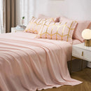 Pink bedding set with gold geometric patterns on a bed in a bedroom.