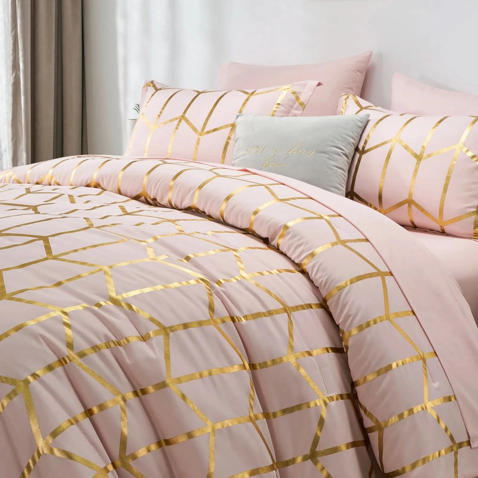 Pink and gold geometric patterned bedding set on a bed with pillows.