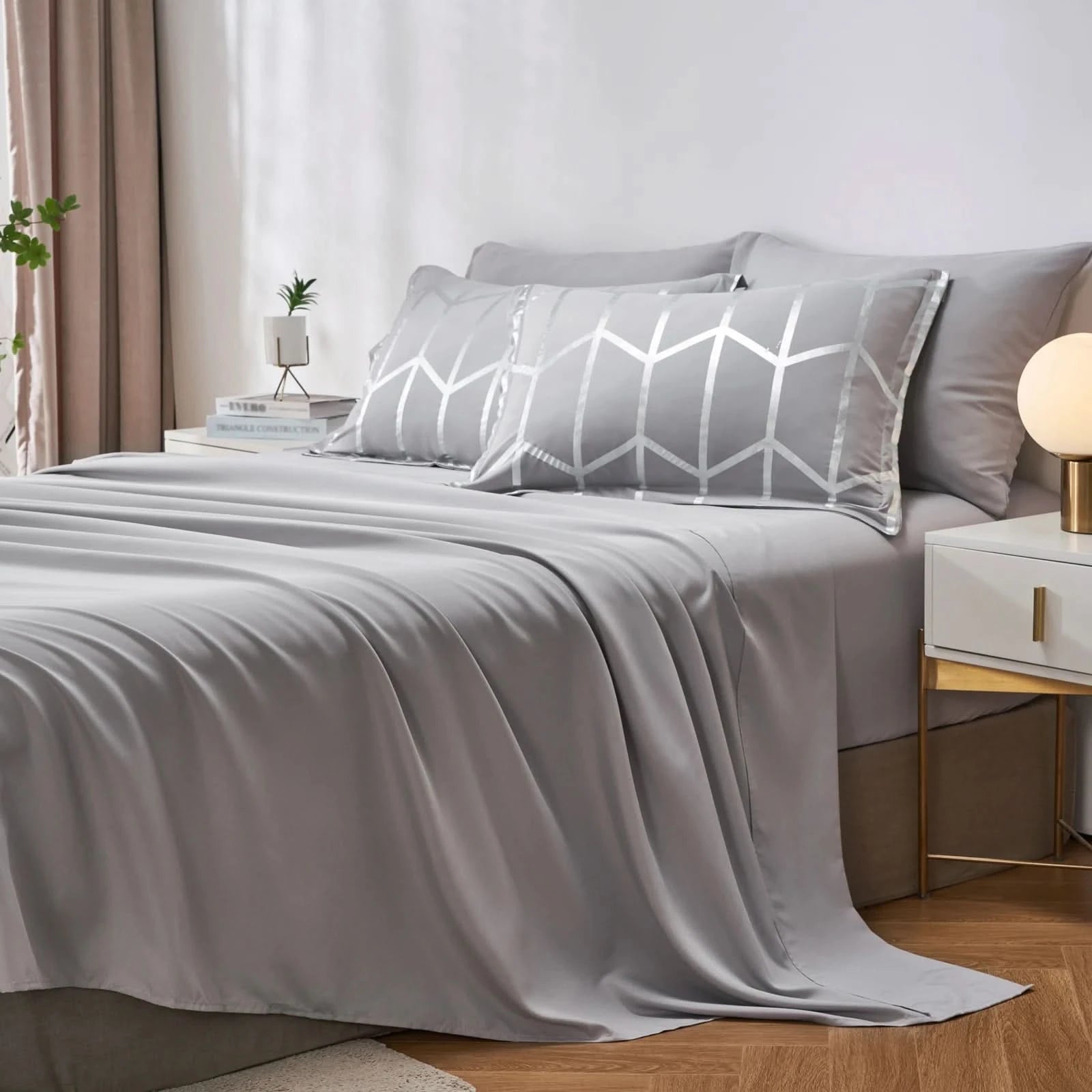 Gray bedding set with geometric pillow on a bed in a bedroom setting.